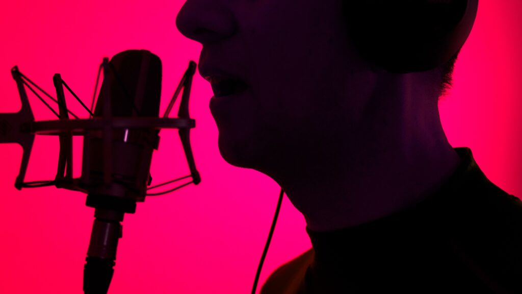 voice-over artist with microphone and stand with bright pink background