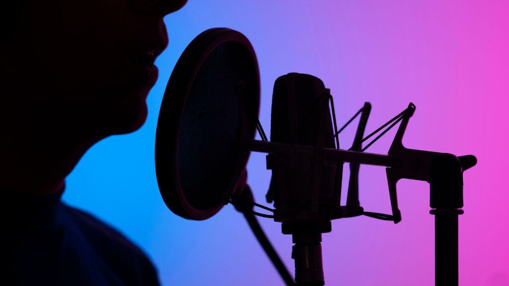 voice-over artist with microphone and stand with purple pink blue background